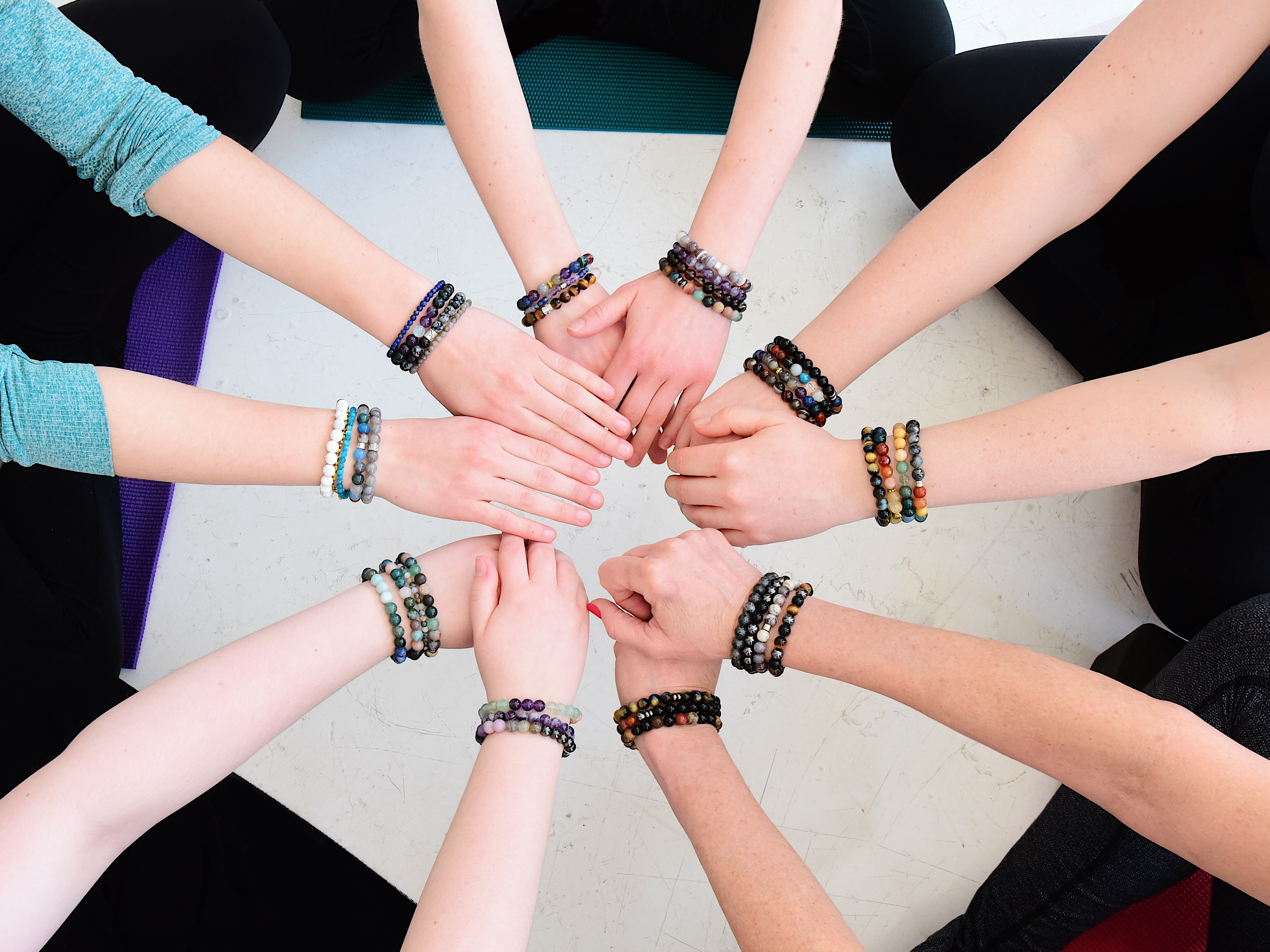 Hands in a circle showing bracelets.