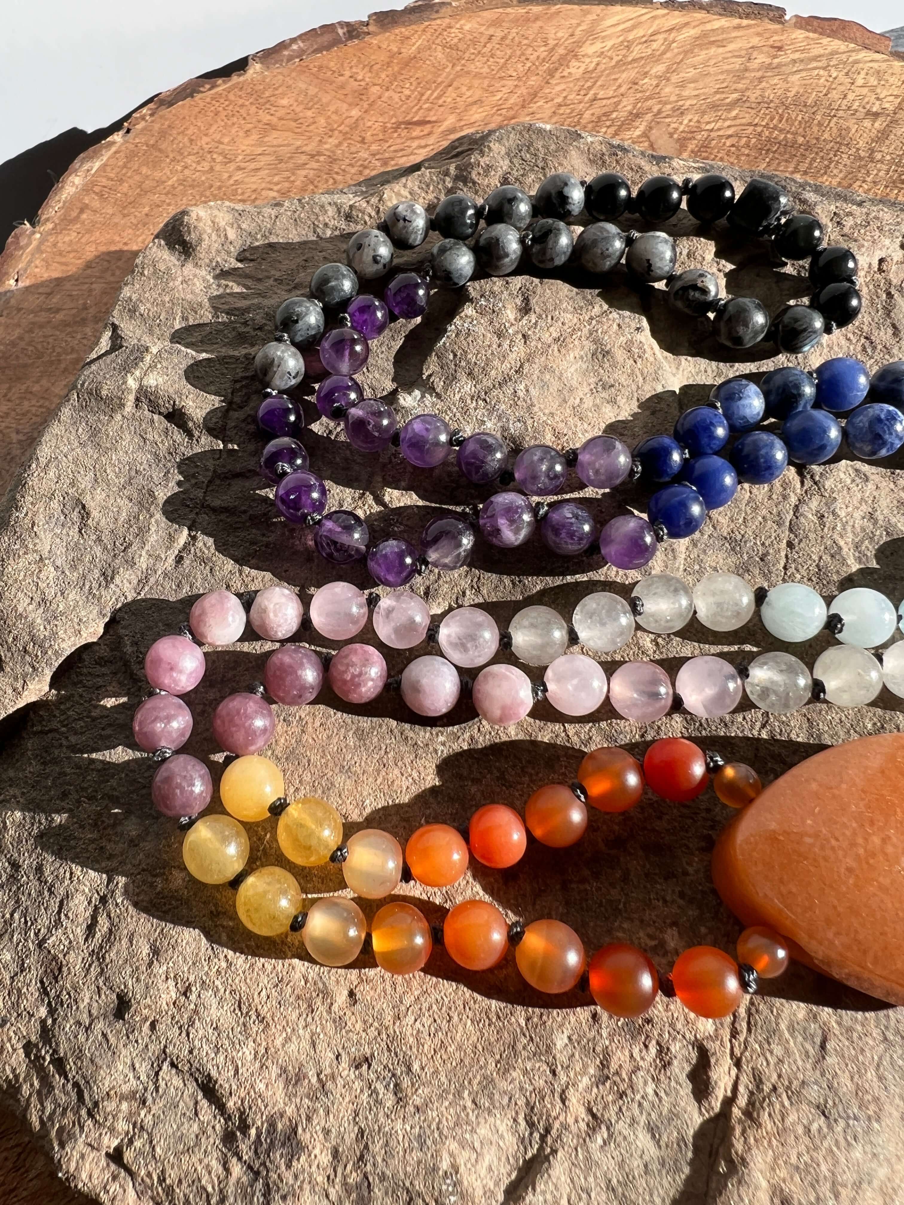 Sunset Mala This mala is made with authentic Carnelian, Yellow Jade, Lepidolite, Moonstone, Aquamarine, Sodalite, Amethyst, Larvikite, Red Aventurine, and Onyx gemstones which give the wearer a sense of being deeply rooted. Zodiac Signs: All. Chakras: All